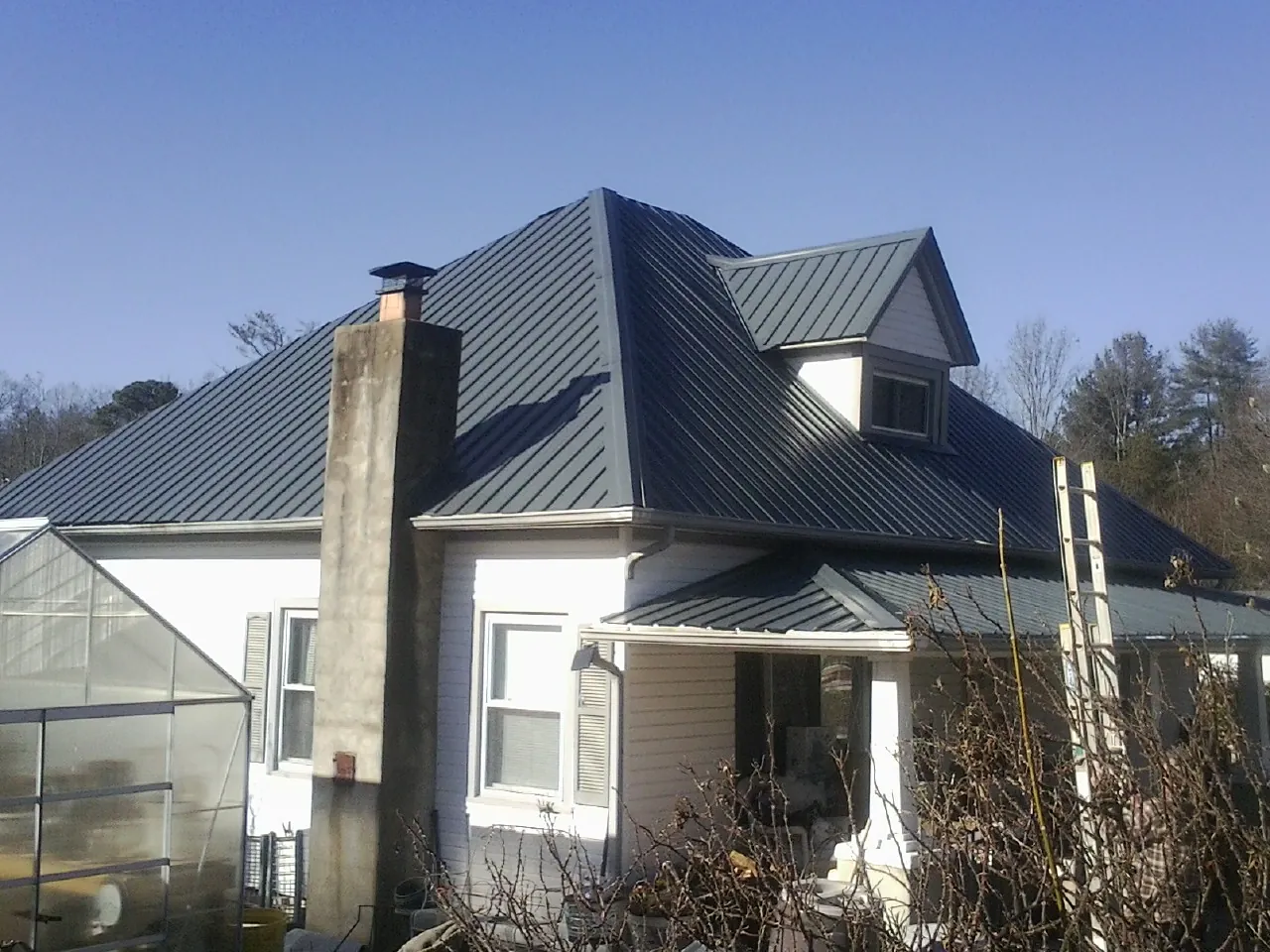 Dark blue standing seam metal roof on a white farmhouse with dormer — Slate & Tile Roof Repair by Roofing Brothers in New Fairfield
