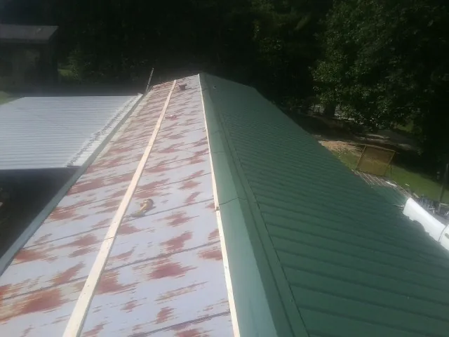 Old rusted panels beside newly installed green metal roofing — Wind Damage Roof Repair by Roofing Brothers in New Fairfield