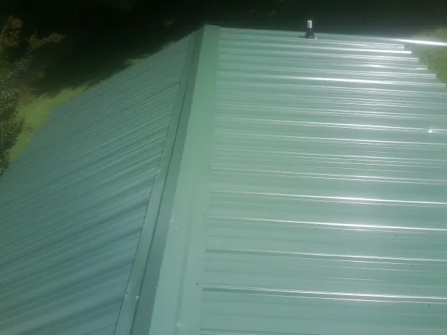New green metal panels meeting at the ridge of a roof — Flat Roof Repair work by our crew in New Fairfield