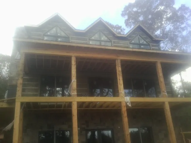 Dormers and porch framing on a large log home under construction — Roof Coating work by our crew in New Fairfield