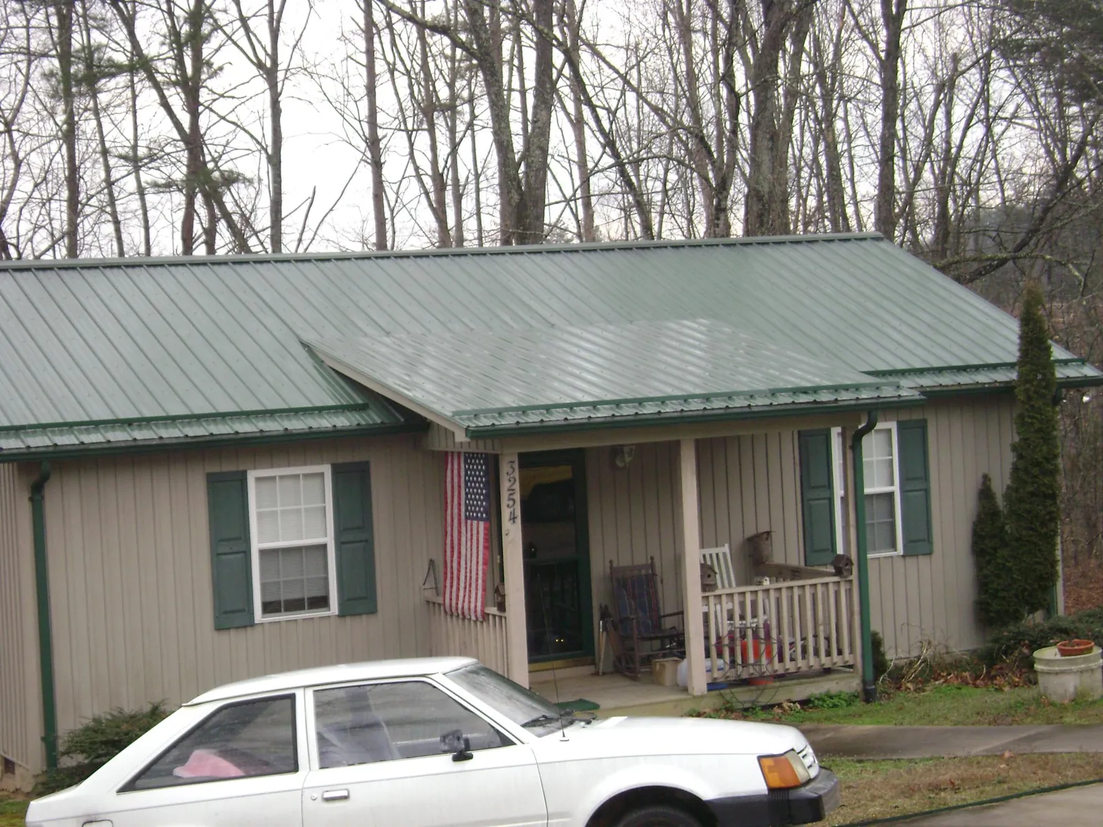 Green metal roof and front porch on a tan sided cottage in New Fairfield