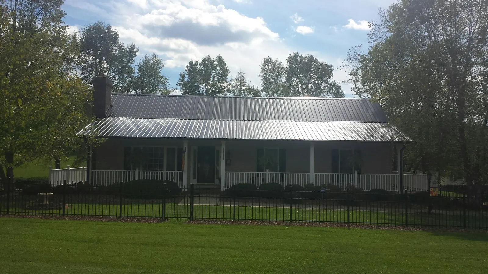 Gray metal roof on a brick ranch with a full width front porch — Gutter Guard Installation work by our crew in New Fairfield