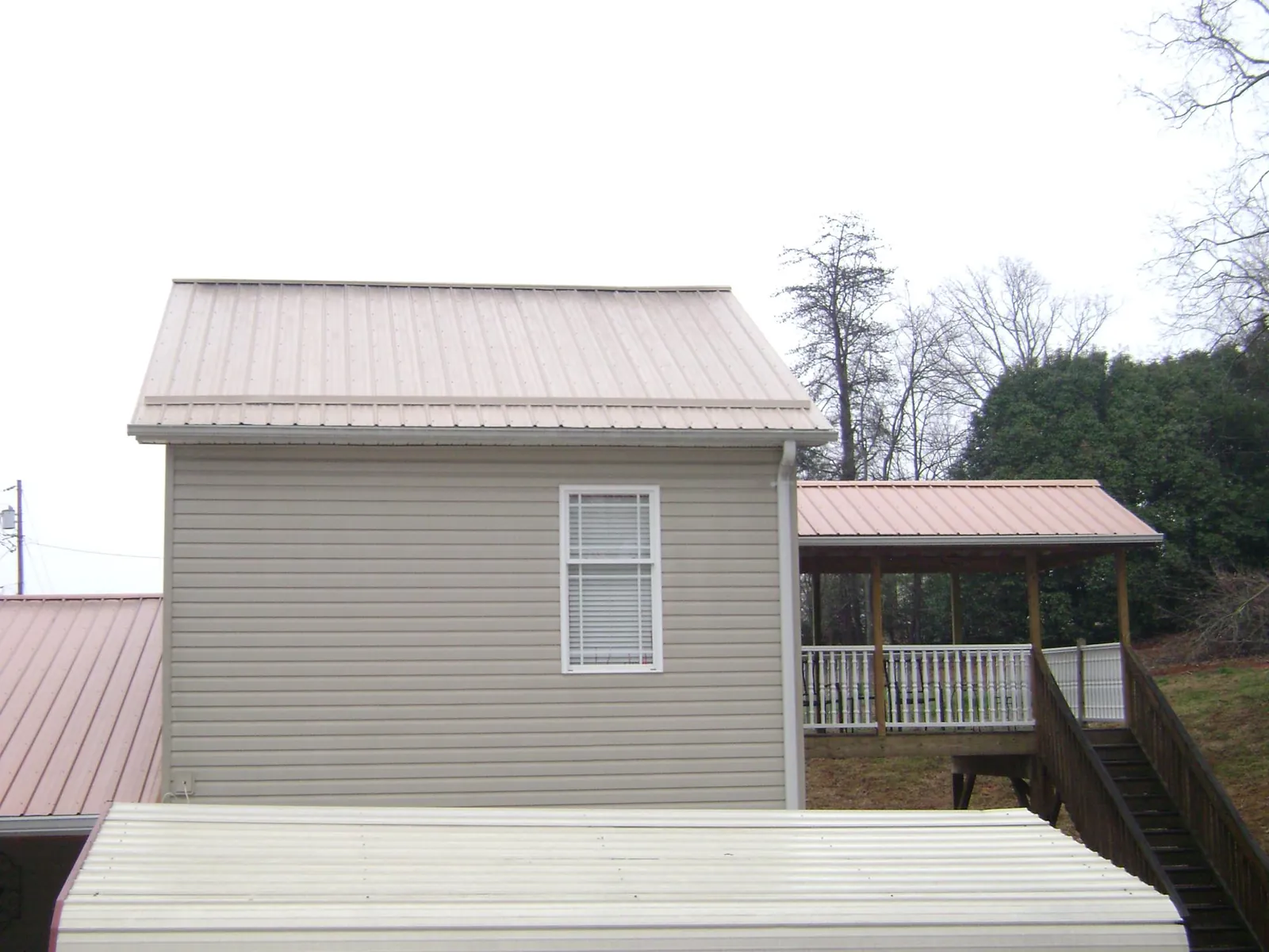 Tan metal roofs on a two story addition and attached porch, from a Roof Replacement job in New Fairfield