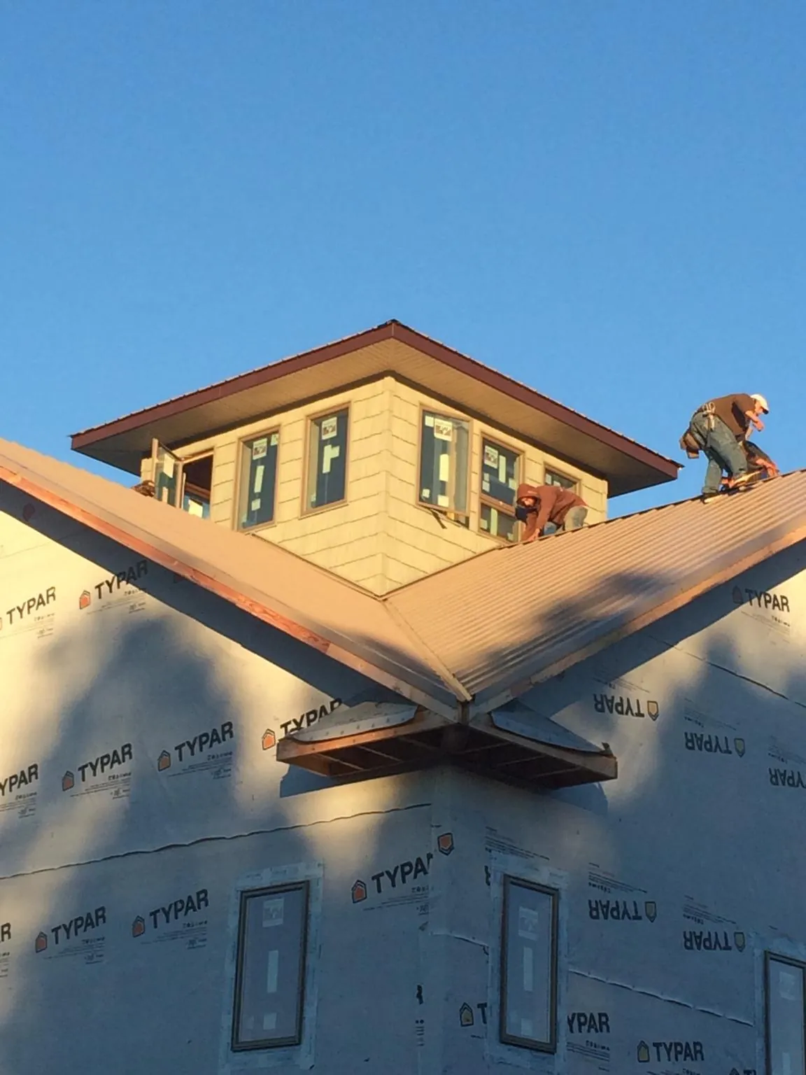 Roofers working around a rooftop cupola on a new metal roof at sunset — Roof Waterproofing in New Fairfield by Roofing Brothers